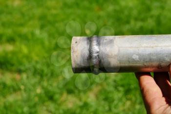 Metal pipe with a welded seam In the hand of a welder's man