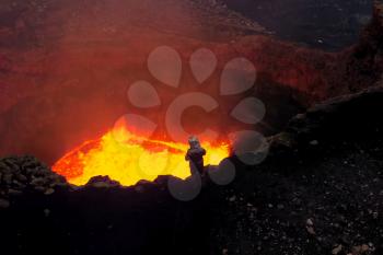Mouth of the volcano with magma. A man in a protective suit near Molten magma in the muzzle.
