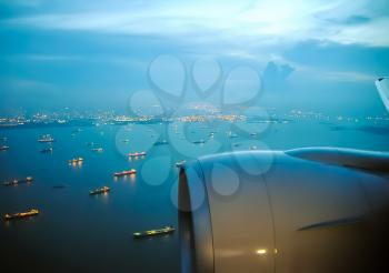 Flight of the aircraft over the port, visible ships on the water. The view from the window of a passenger plane during the flight, the wing of the turbine engine of the aircraft.