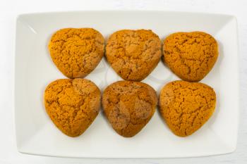 Heart shaped oatmeal cookies on white plate. Homemade breakfast cookies. Valentines Day or Mothers day sweet pastry.