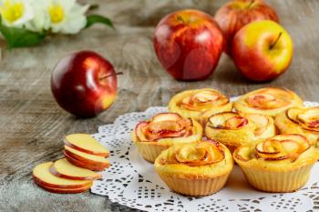 Apple shaped roses muffins on wooden background. Sweet apple dessert pie. Homemade apple rose pastry. 