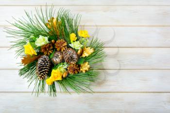 Christmas wreath with yellow silk roses and golden pinecones. Christmas party decoration. Christmas greeting background. Copy space. 
