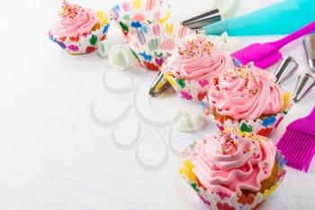 Decorated pink birthday cupcakes  and cookware. Birthday homemade cupcakes decorating process. 
Sweet dessert  pastry with whipped cream. 
