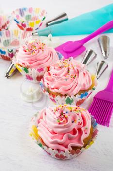 Pink cupcakes  and kitchen utensils, vertical. Birthday cupcakes. Homemade cupcake. Sweet dessert. Gourmet cupcakes. Sweet cupcake. Sweet pastry.  