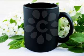 Black coffee mug mockup with apple blossom. Empty mug mockup for product presentation. Coffee cup mock-up for promotion brand or design. 