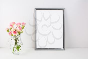 Silver frame mockup with pink roses. Portrait or poster white frame mockup. Empty white frame mockup for presentation artwork.