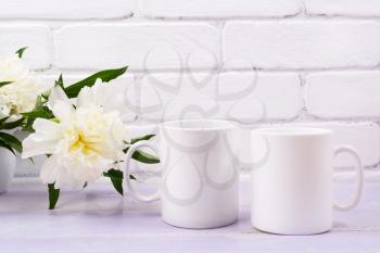 Two white coffee  mug mockup with pale ivory peony flower.  Empty mug mock up for design promotion.   