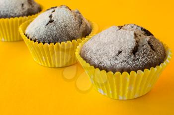Chocolate muffins in paper cupcake holder on yellow background, selective focus