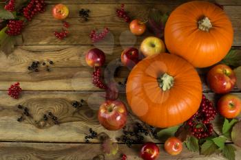 Ripe pumpkins, apples, berries and leaves on wooden background. Selective focus. The toning