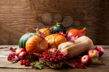 Abundant harvest concept with pumpkins, apples, berries and fall leaves. Thanksgiving background with pumpkins and seasonal berries. Copyspace