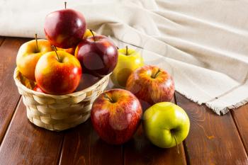 Apples in the small wicker basket on dark wooden background. Healthy eating concept with fresh fruits. 