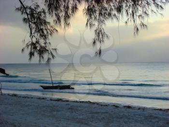 The first light in the morning sky before sunrise on tropical sea sand beach and boat in sea waves, Mombasa, Kenya