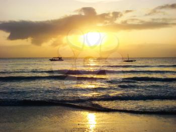Morning sun, sunrise sky and clouds above sea waves on tropical sea sand beach, boats on skyline, Mombasa, Kenya                             