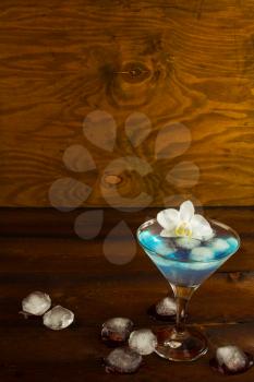 Blue cocktail in a martini glass with white orchid, vertical, copy space. Blue Martini. Blue curacao liqueur.  Blue margarita. Blue Hawaiian cocktail