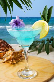 Blue Hawaiian cocktail on the tropical beach. Iced blue cosmopolitan cocktail. Blue Lagoon margarita martini cocktail. Summer beach alcohol drink