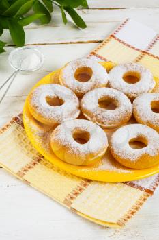 Caster sugar powdered donuts on yellow plate. Sweet dessert. Sweet pastry doughnuts.  Hanukkah homemade donuts.