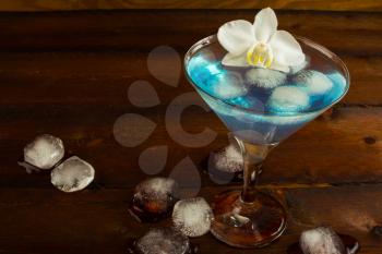 Cocktail Blue Martini on the dark wooden background. Blue cocktail. Blue Martini. Blue Hawaiian cocktail. Blue curacao liqueur.  Blue margarita