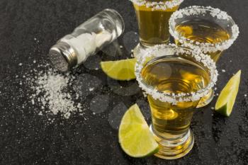 Gold tequila shots with lime on black background. Gold Mexican tequila. Tequila shot. Tequila. 