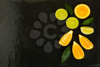 Limes and lemons on black background, copy space. Fresh food. Ripe fruit. Citrus fruit. Vegetarian food. Fresh fruit. Mixed fruit. Fruit background.