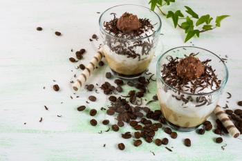 Whipped coffee cocktail with chocolate in glasses on light green background. Coffee creamy dessert with cocoa. 