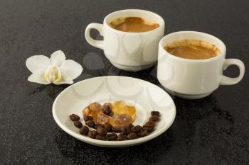White coffee cups and white orchid on the black background. Cup of coffee. Coffee break. Morning coffee. Coffee cup