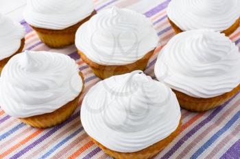 White cupcakes on the linen napkin top view. Sweet gourmet dessert. Homemade cupcakes with whipped cream.  Sweet pastry