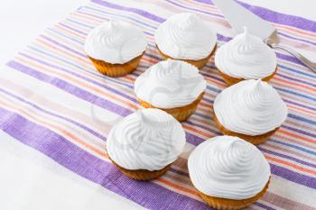 White cupcakes row on the linen napkin. Birthday cupcakes. Homemade cupcake. Sweet cupcake. Sweet dessert. Gourmet cupcakes. Sweet pastry.  