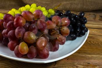 Bunch of white, red and dark grapes on a dark wooden background. Cluster of grapes. Bunch of grapes. Custer grapes. Bunch grapes. Grapes. Grape
