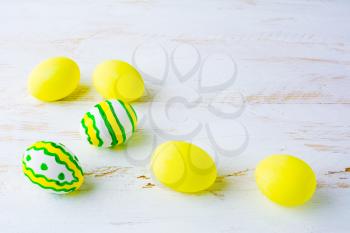 Decorated Easter white green yellow eggs on a white wooden background, space for text, copy space