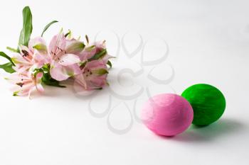 Pink and green Easter eggs with floral design and pink flowers on a white background. Easter background. Easter background. Easter symbol. Copy space