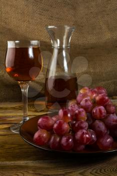 Bunch of red grapes and a glass of wine on a dark wooden background. Cluster of grapes. Bunch of grapes. Cluster grapes.  Bunch grapes. Grapes. Grape. Glass of wine. Glass wine. Grape vine