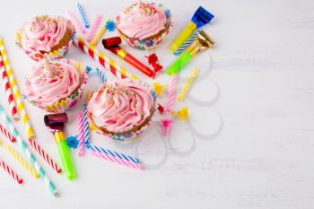Birthday background with pink cupcakes and birthday candles. Homemade cupcakes with whipped cream. Holiday party background.
