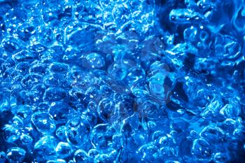 Blue splash and ripples on the stream water.  Splash water surface texture. Blue water background
