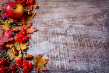 Border of fruits and fall leaves on the dark wooden background. Thanksgiving background with seasonal fruits.  Copy space