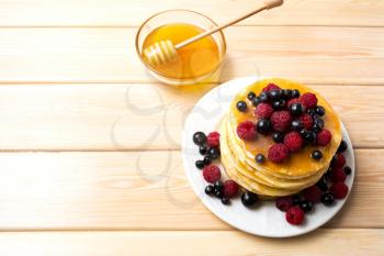 Breakfast pancakes with honey and fresh berries. Stack of homemade pancakes served with blueberry, raspberry and blackcurrant.