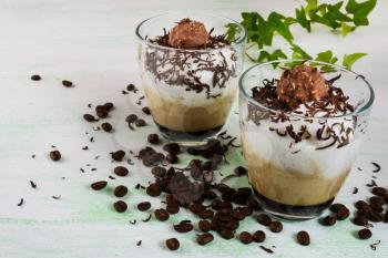 Chocolate milkshake with whipped cream on light green background. Coffee creamy dessert with chocolate. 