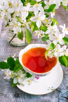 Cup of tea on wooden table and apple blossom. Tea time concept. Breakfast tea cup served with flowers.