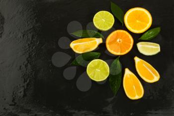 Detox concept with fresh fruits on black background. Healthy eating concept with ripe mixed citrus. Lime, lemon and orange fruit background. 