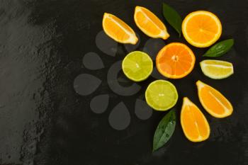 Detox concept with lemon, orange and lime on black background. Healthy eating concept with ripe mixed citrus. Lime, lemon and orange fruit background. 