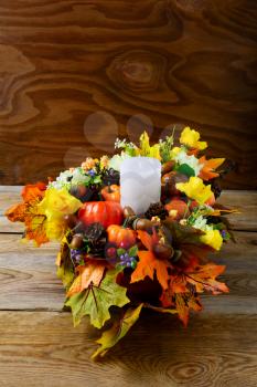 Fall table centerpiece with candle and silk maple leaves, vertical. Thanksgiving greeting with fall decor. Fall centerpiece. Thanksgiving background. 