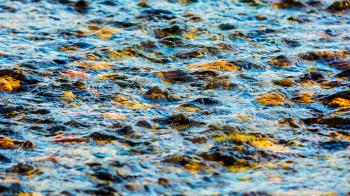 Flecks of sunlight and ripples on the water of river.  Blue water surface texture background