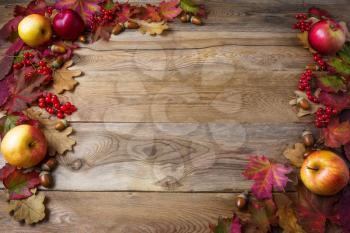 Frame of apples, acorns, berries and fall leaves on dark wooden background. Thanksgiving background with seasonal berries and fruits. Abundant harvest concept.