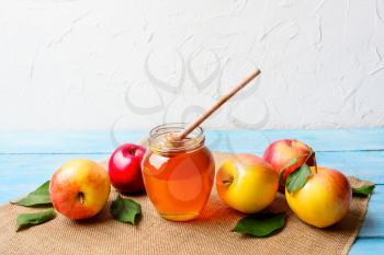 Glass honey jar with dipper and apples, copy space. Rosh hashanah concept. Jewesh new year symbols. 