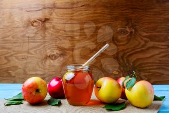 Glass honey jar with dipper and fresh apples, copy space. Rosh hashanah concept. Jewesh new year symbols. 