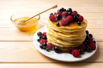 Homemade pancakes with honey and fresh berries. Stack of breakfast pancakes served with blueberry, raspberry and blackcurrant.