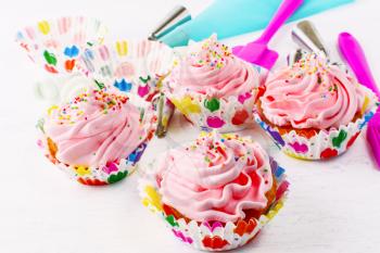 Homemade pink birthday cupcakes  and cookware background. Birthday cupcake with pink whipped cream. Homemade cupcakes decorated for party. 