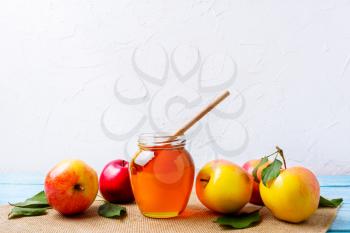 Honey jar with dipper and apples on white background. Rosh hashanah concept. Jewesh new year symbols. Copy space.