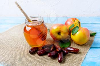Honey jar, dates and apples on burlap napkin. Rosh hashanah concept. Jewesh new year symbols. 