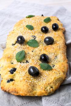 Italian bread with olive, garlic and herbs. Homemade traditional Italian bread focaccia on the linen napkin.