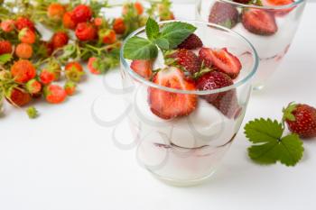 Layered strawberry dessert with yogurt on white background. Diet yogurt dessert with ripe strawberry.